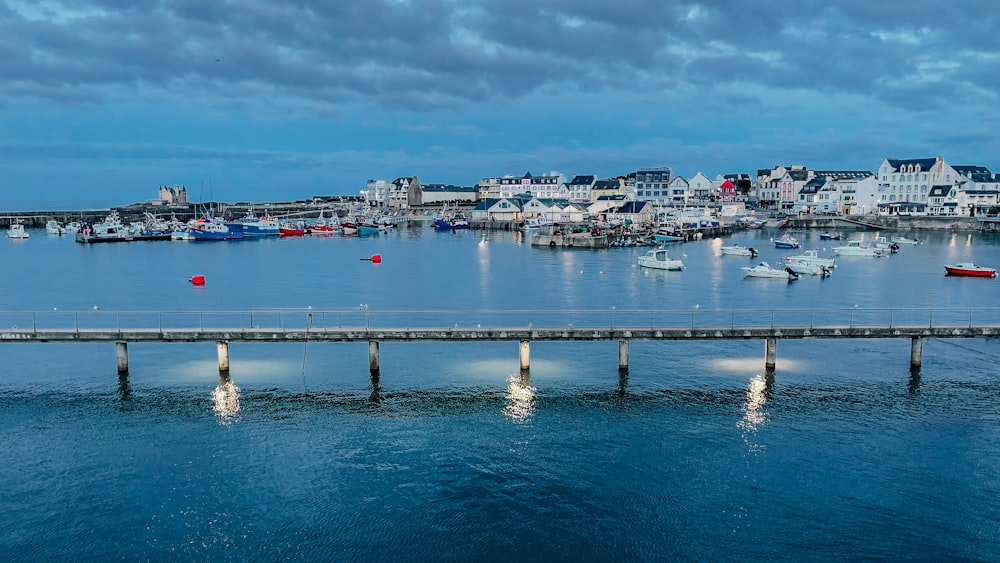 a pier with boats in the water and houses in the background