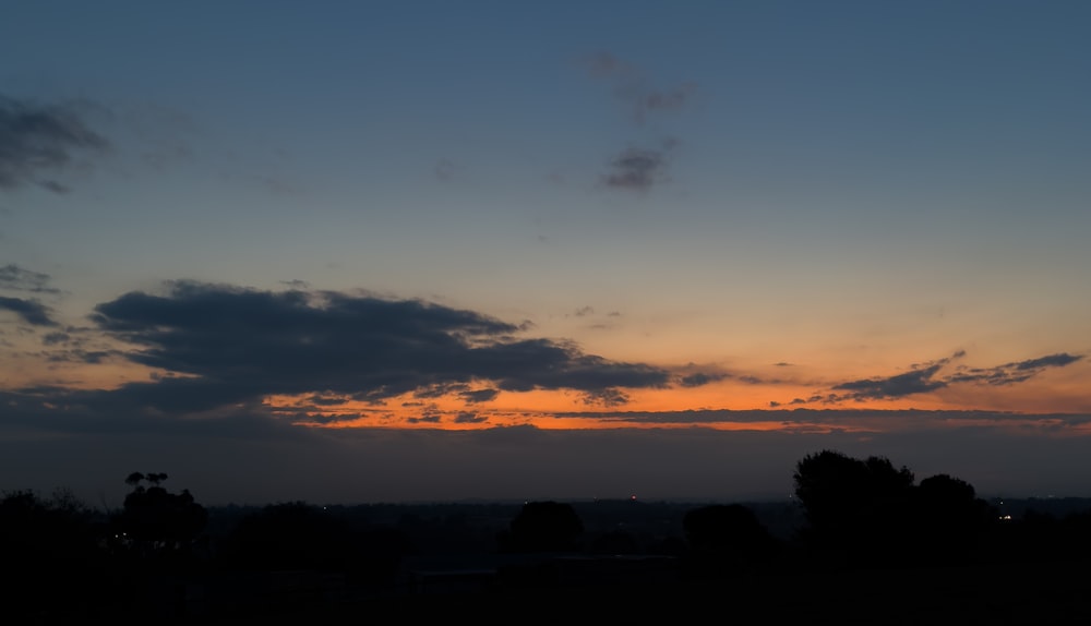 the sun is setting over a field with trees