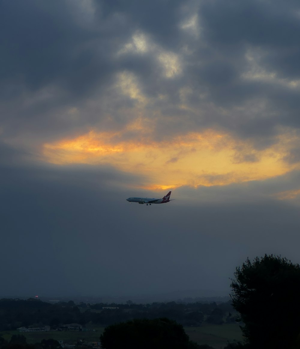 a plane flying in the sky at sunset