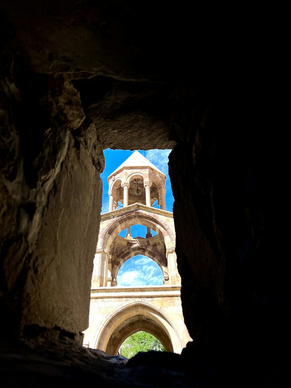 a view of a clock tower through a cave
