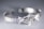 A close-up view of a delicately crafted bracelet featuring an intricate design with sparkling diamonds and detailed metalwork. The bracelet has a woven pattern and ornate central motif resembling leaves and flowers. The background is softly blurred creating a bokeh effect, highlighting the elegance of the jewelry.