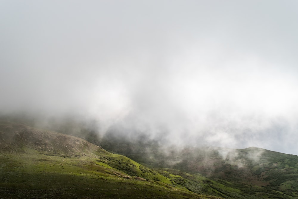 uma colina coberta de nevoeiro e nuvens em um dia nublado