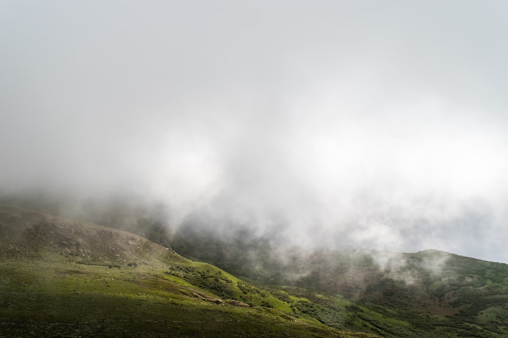 a hill covered in fog and clouds on a cloudy day