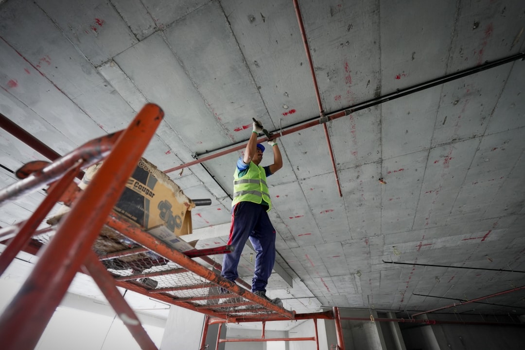 a man standing on a ladder working on a ceiling,