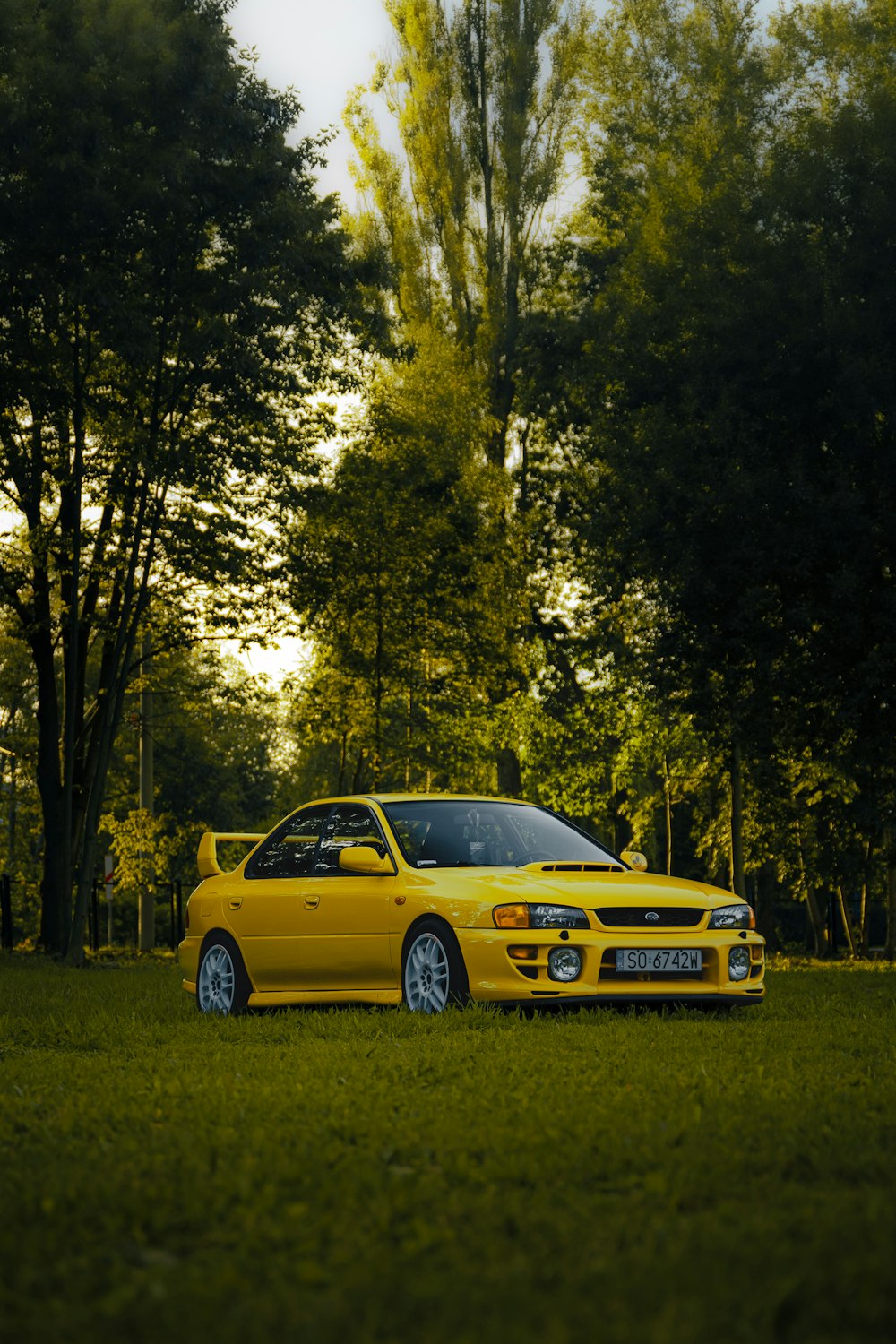 a yellow car parked in a grassy field
