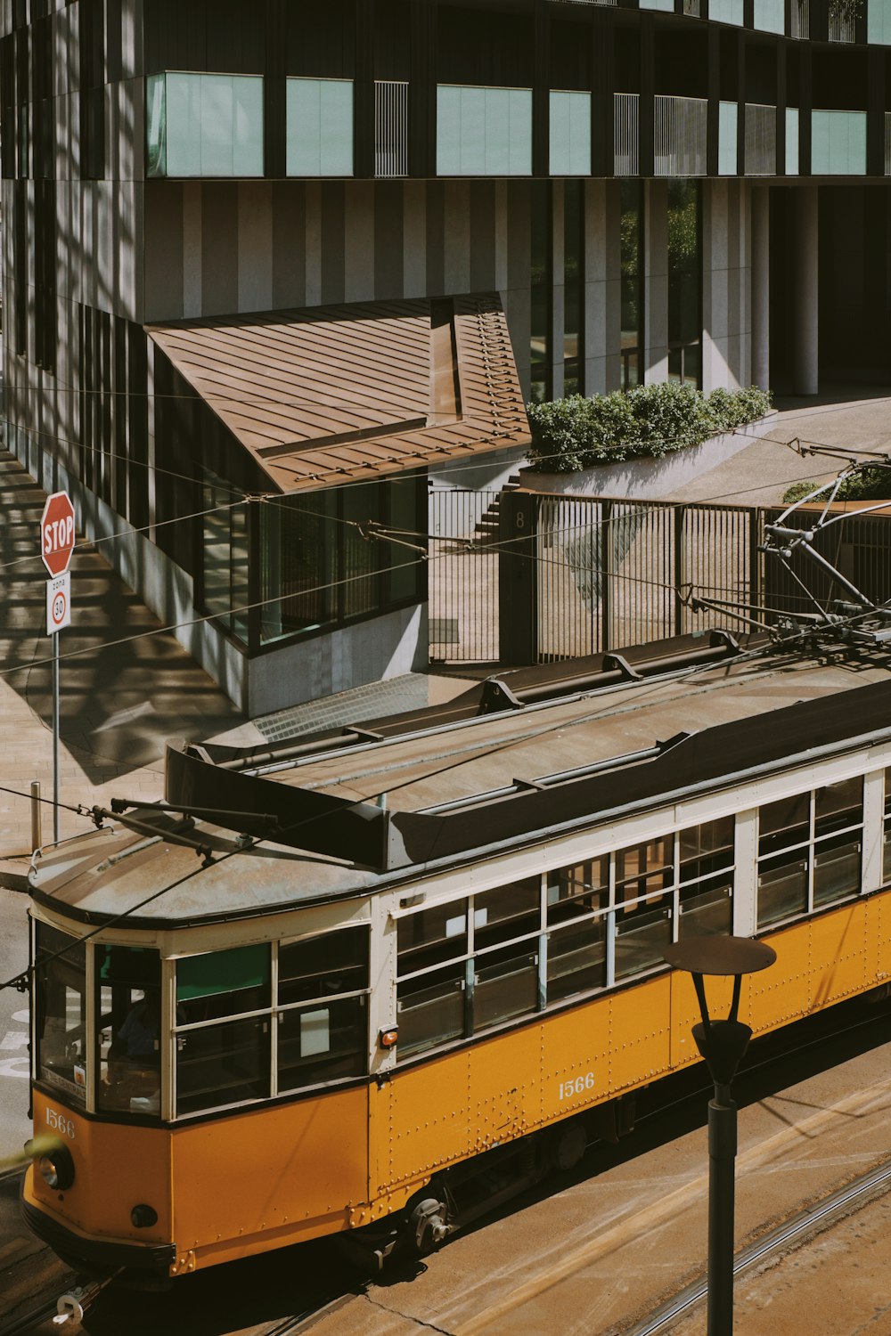 a yellow and white train traveling past a tall building