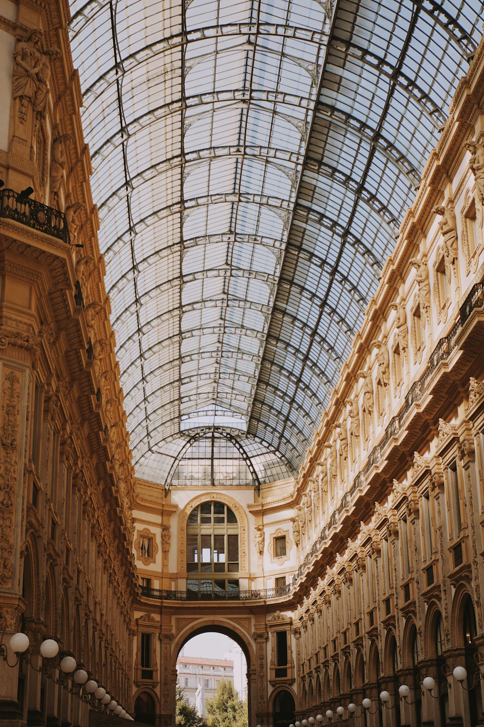 Grand hallway features high glass ceiling with ornate columns and large archway above