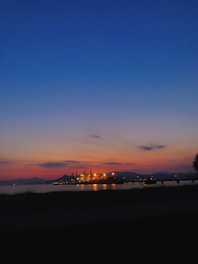 A vibrant refinery at sunset with glowing pipelines and workers in safety gear.