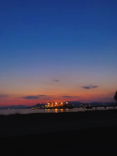 A sleek diesel generator set against a backdrop of a modern industrial facility at dusk, illuminated with subtle electric orange accents.