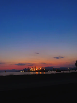 A panoramic view of a sprawling power and water treatment plant under a vibrant sunset sky.