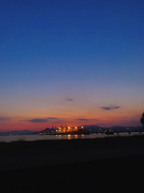 A sleek diesel generator set against a backdrop of a modern industrial facility at dusk, illuminated with subtle electric orange accents.