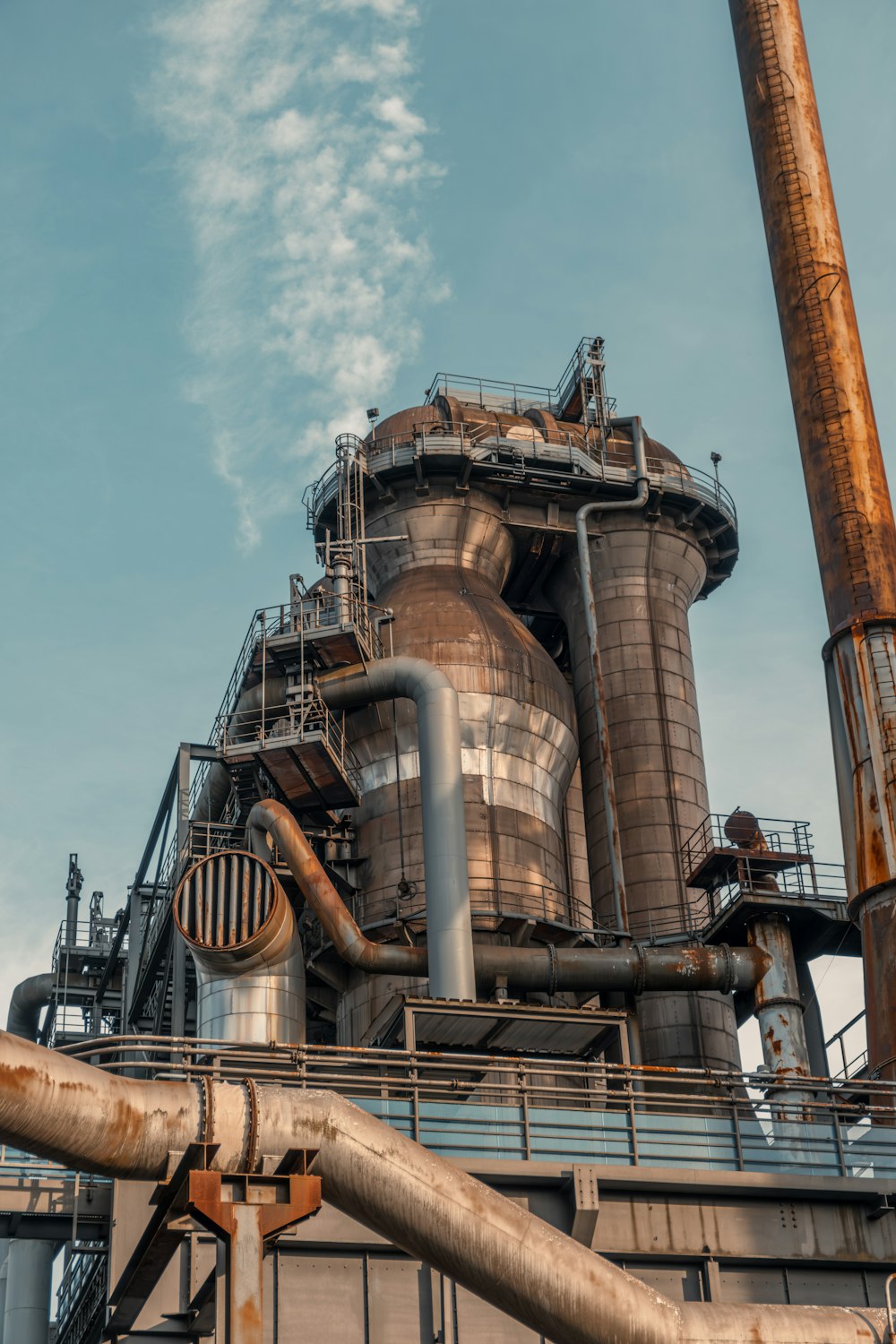 a large industrial building with pipes and a sky background