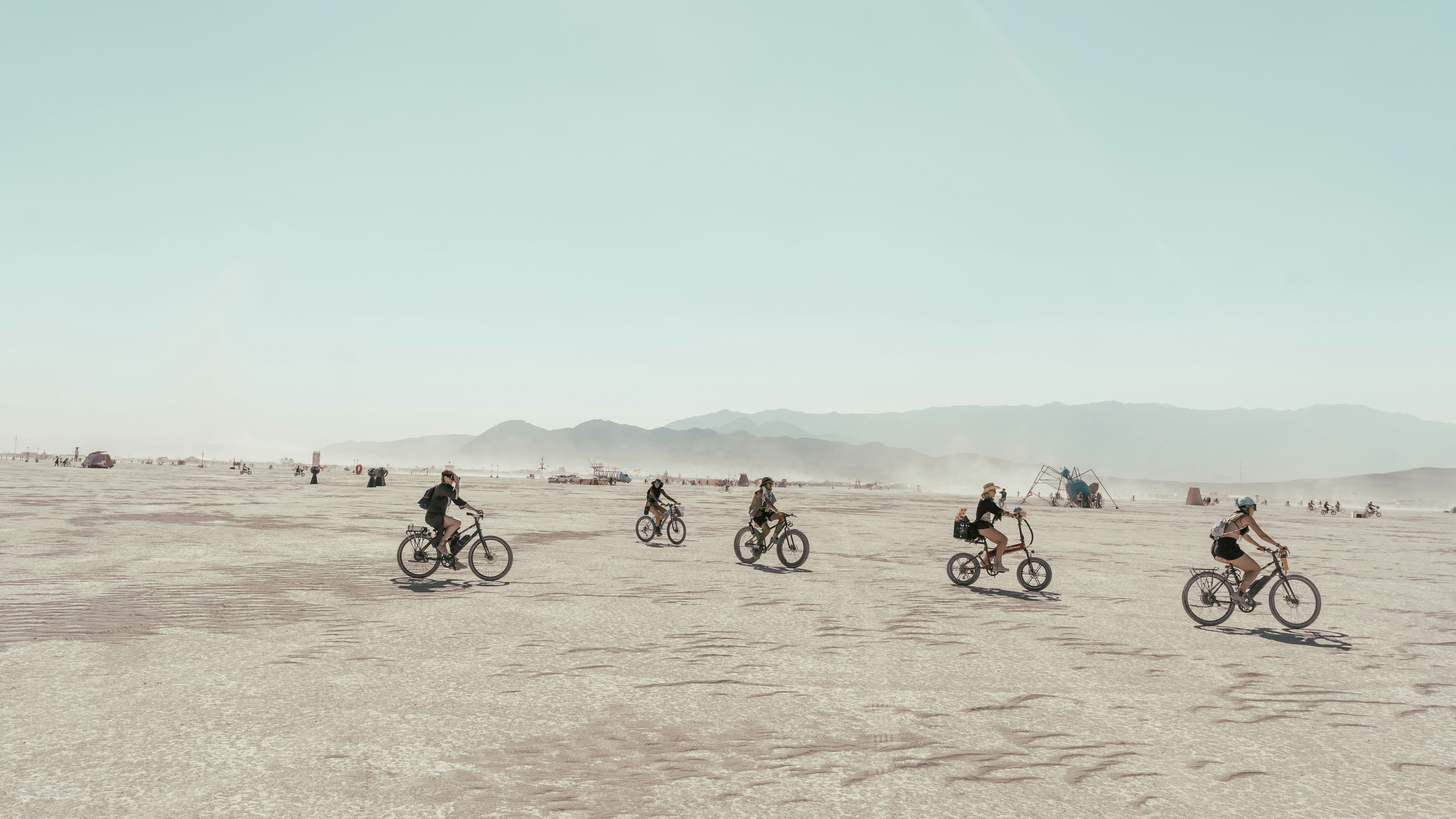 a group of people riding bikes across a desert