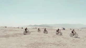 a group of people riding bikes across a desert