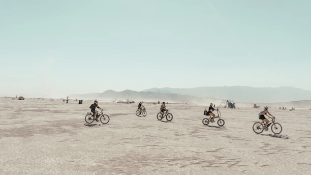 a group of people riding bikes across a desert