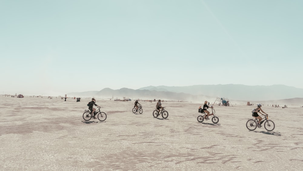 a group of people riding bikes across a desert
