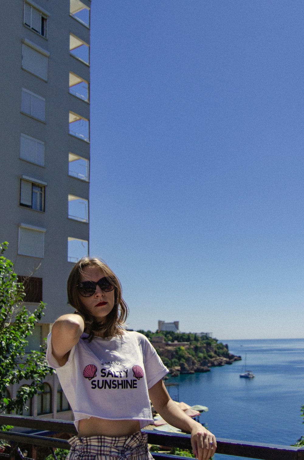 a woman standing on a balcony next to a building