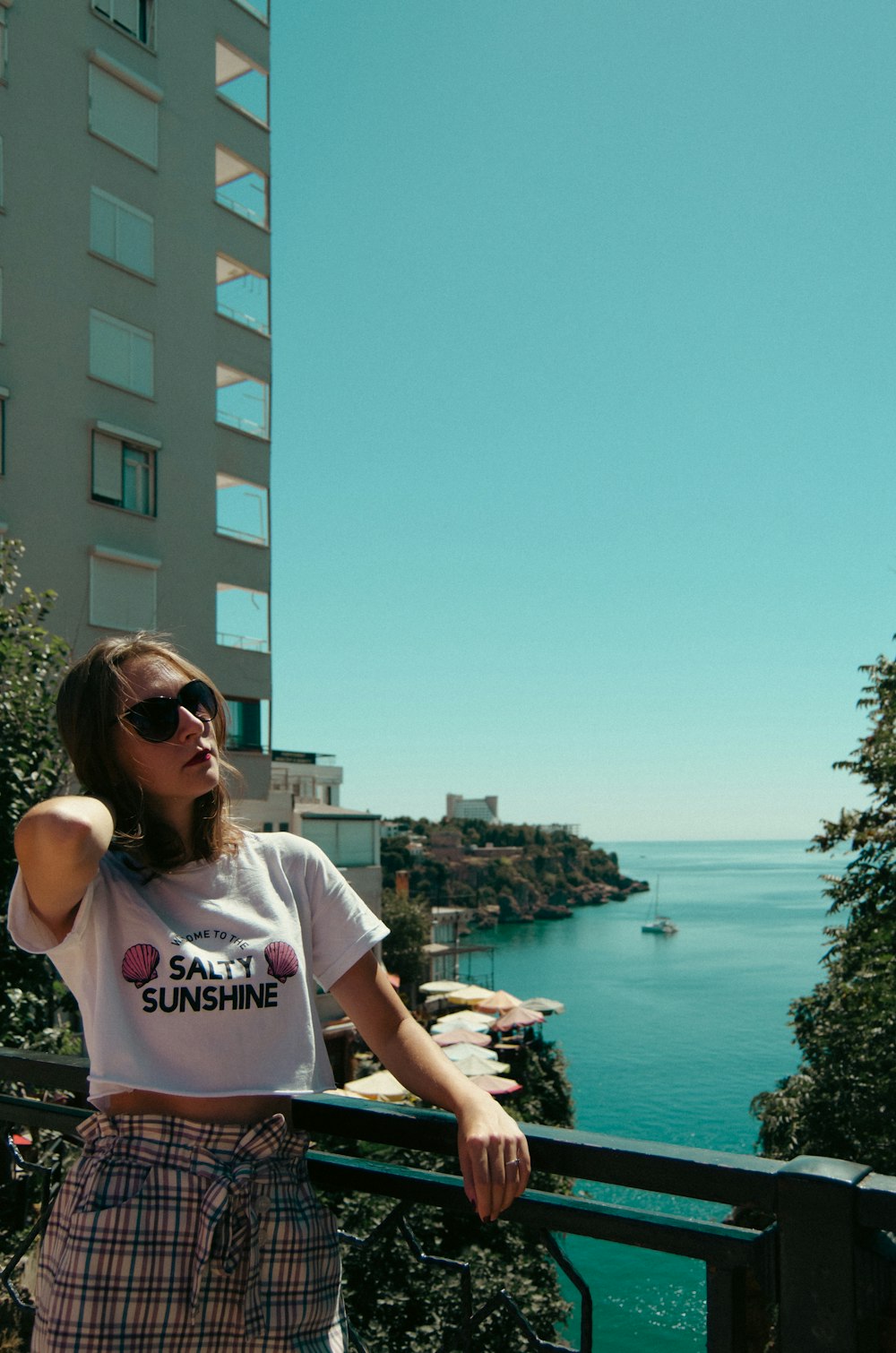 a woman standing on a balcony next to a body of water