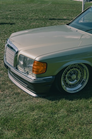 A classic vintage car shining under natural sunlight in a large open field.