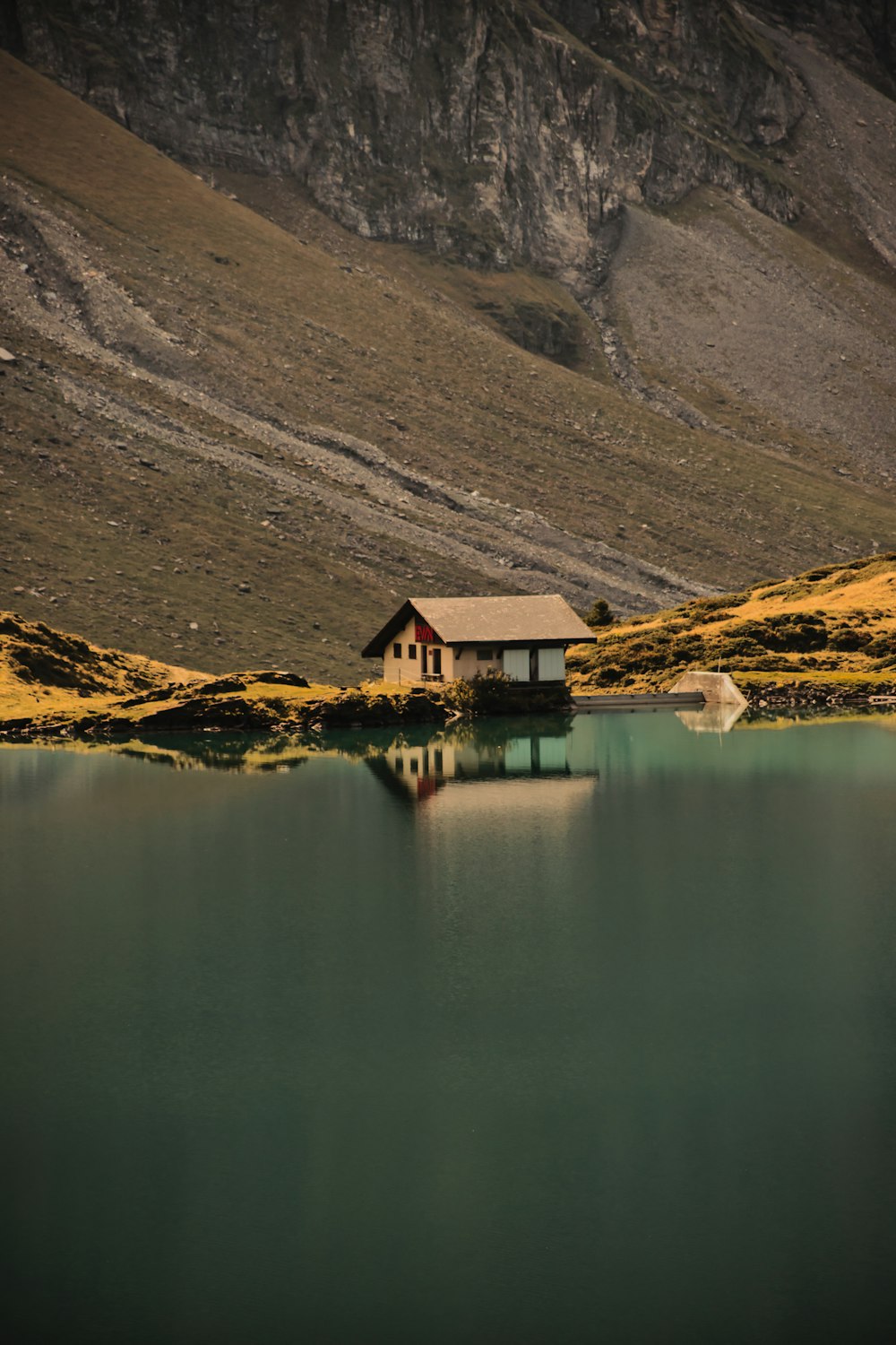uma casa sentada no topo de uma montanha ao lado de um corpo de água