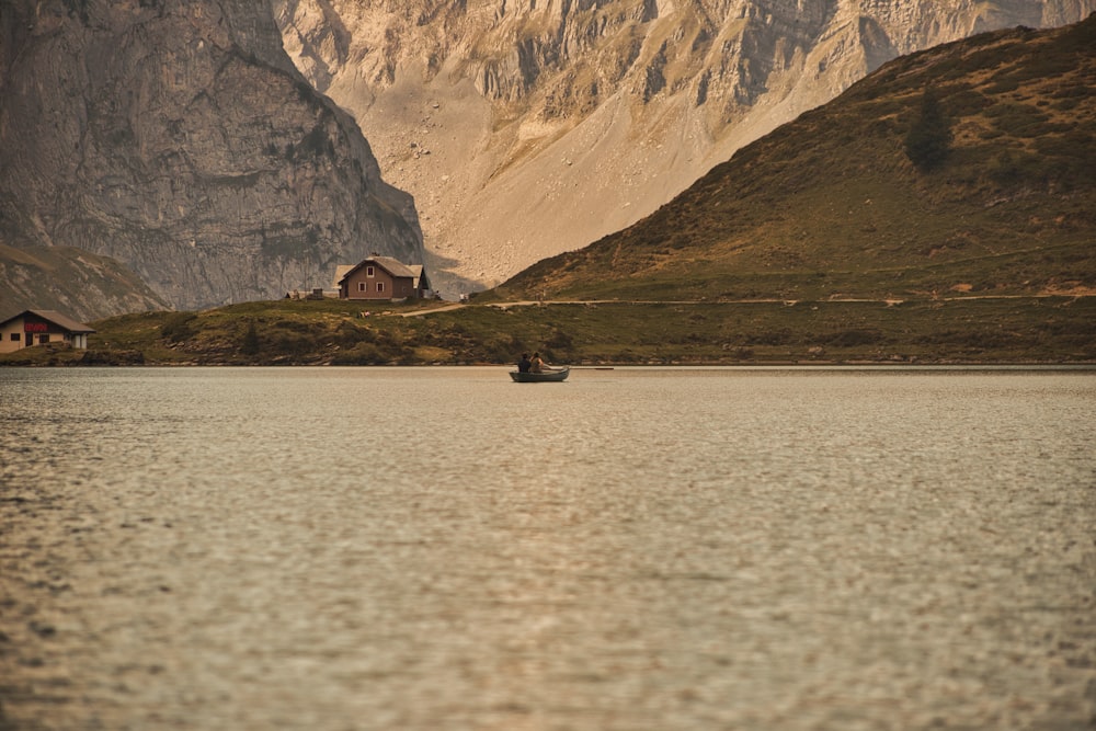 a boat floating on top of a lake next to a mountain