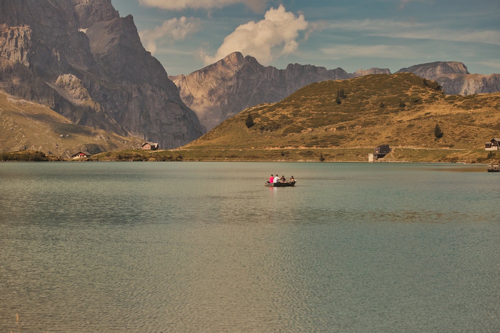 um pequeno barco flutuando no topo de um lago cercado por montanhas