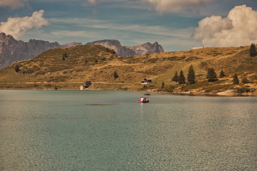 a boat floating on top of a lake surrounded by mountains