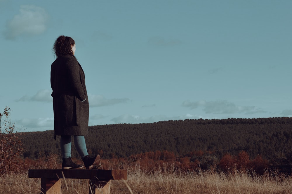 a woman standing on top of a wooden bench