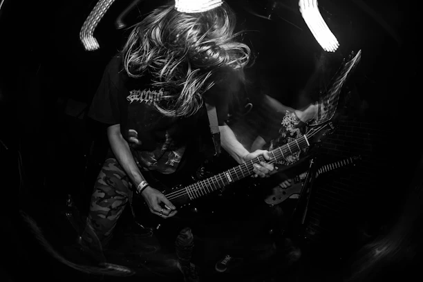 Black-and-white photo capturing a dynamic concert scene with sharp shadows and textured concrete backdrop.