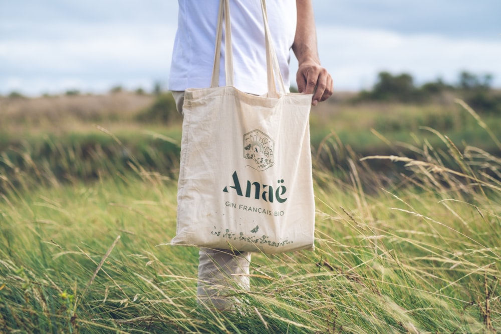 a person holding a bag in a field of tall grass