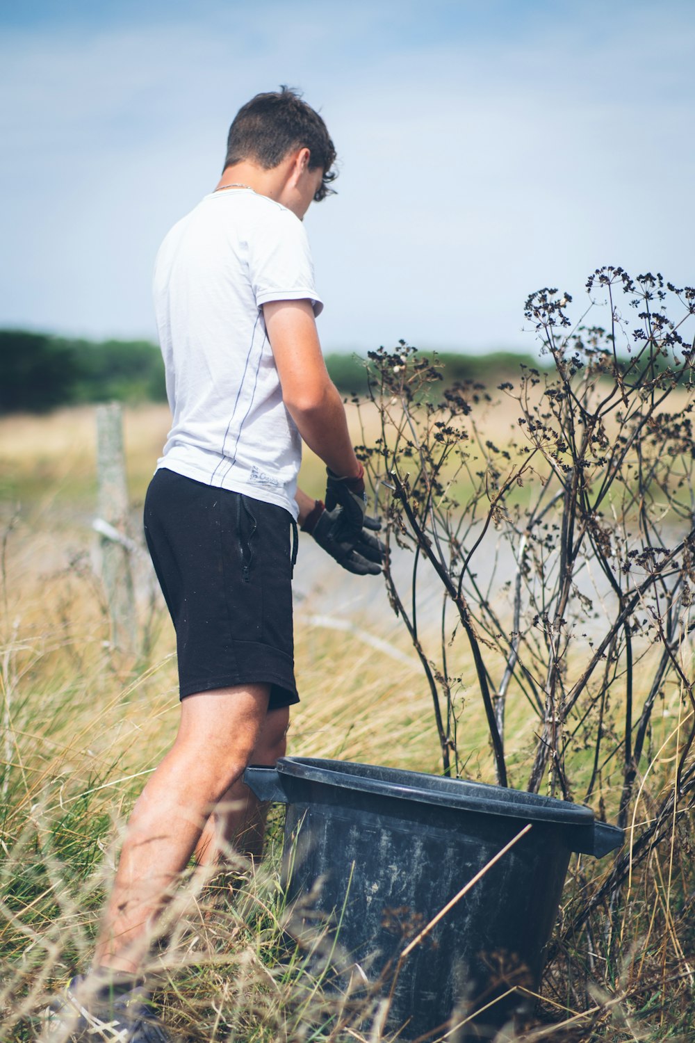 a man standing next to a trash can in a field