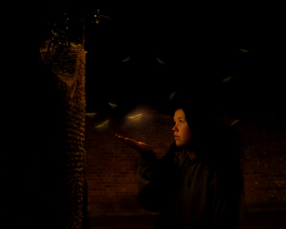 a woman standing in the dark with a bunch of birds flying around her
