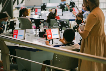 A friendly teacher guiding a child through an interactive AI lesson on a tablet.