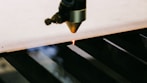 Close-up of a precision laser cutting machine slicing through a sheet of metal with sparks flying.