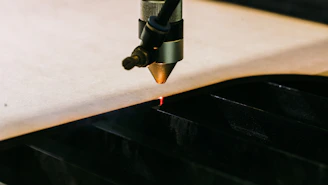 Close-up of a laser cutting machine in action on a wooden material.