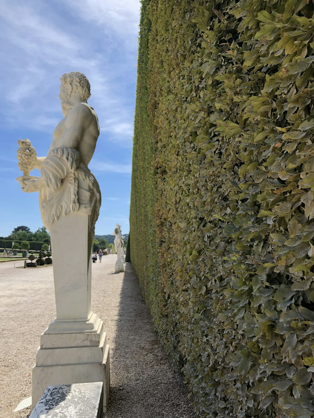 a statue of a man sitting next to a hedge