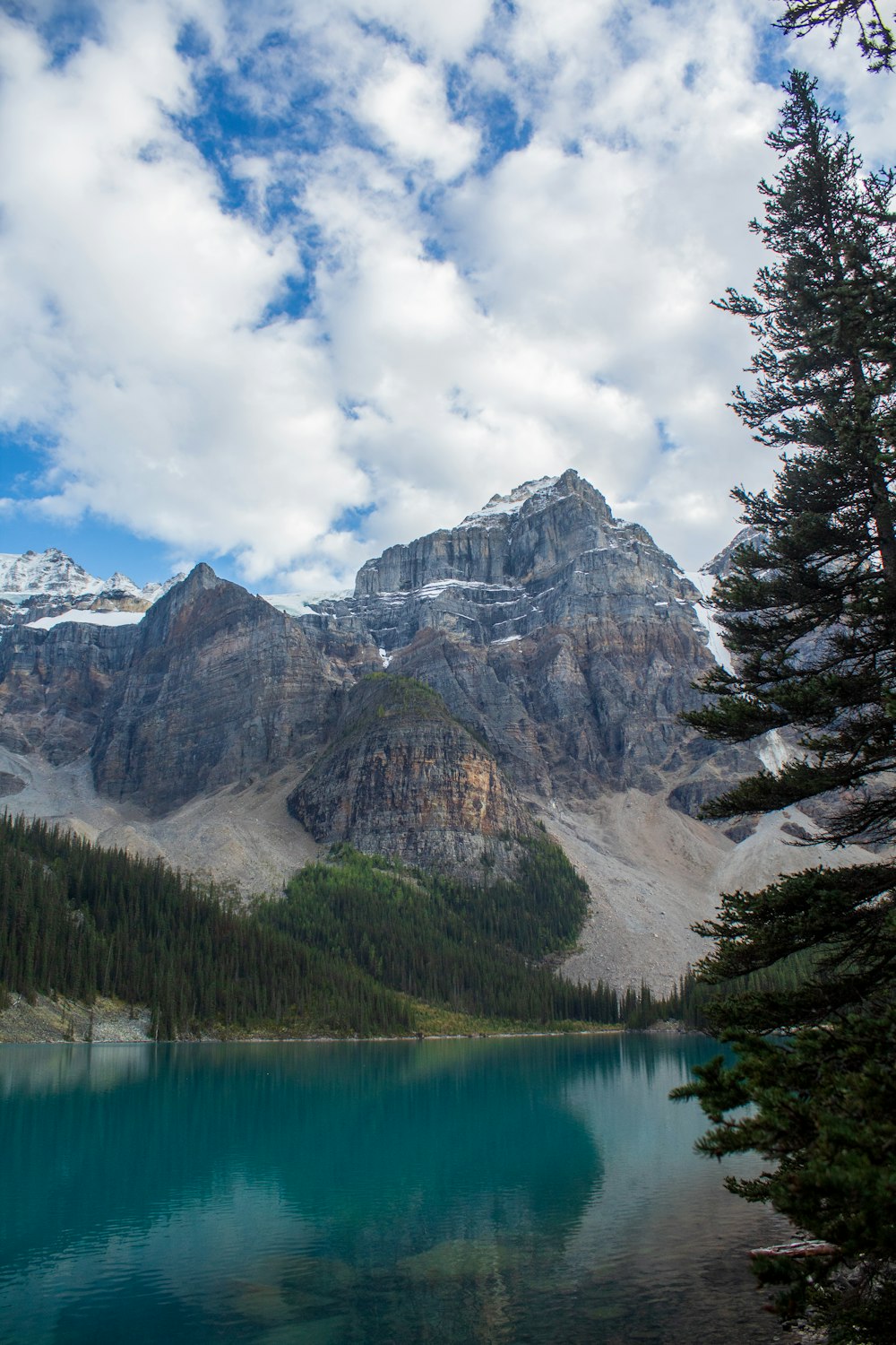 a lake surrounded by mountains under a cloudy sky