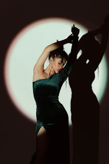 An elegant woman draped in dark velvet, standing against a midnight noir backdrop with stars.
