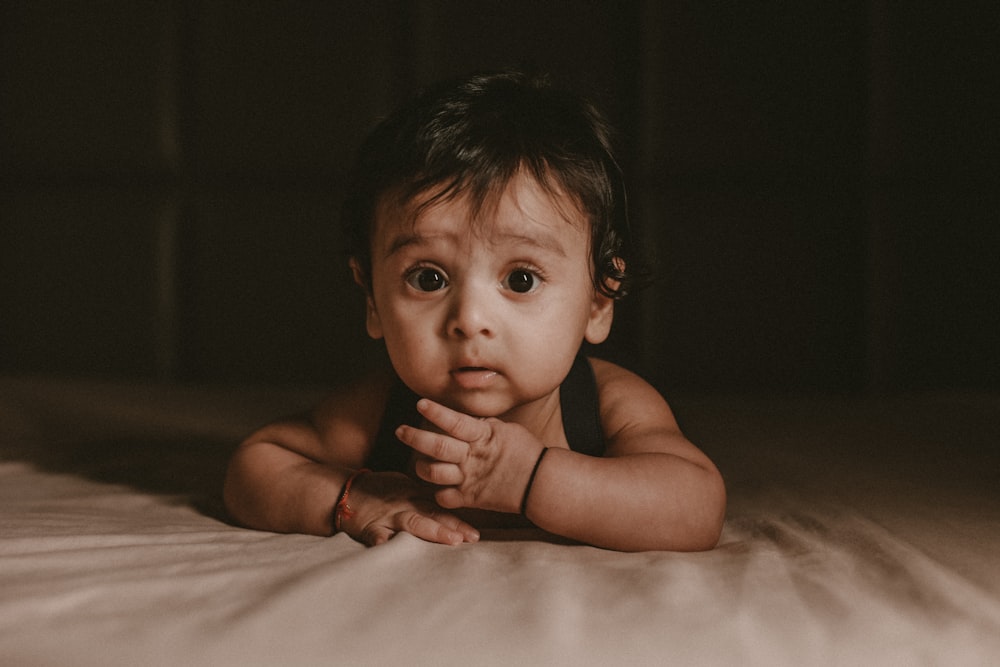 a baby laying on a bed looking at the camera