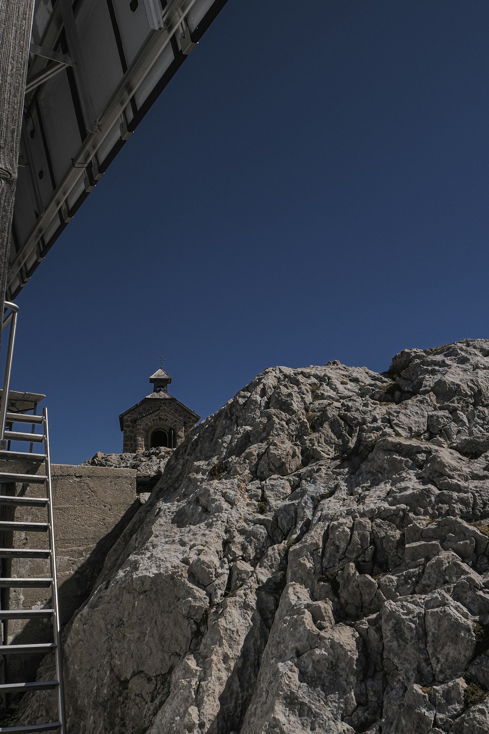 a ladder going up a rocky hill next to a building