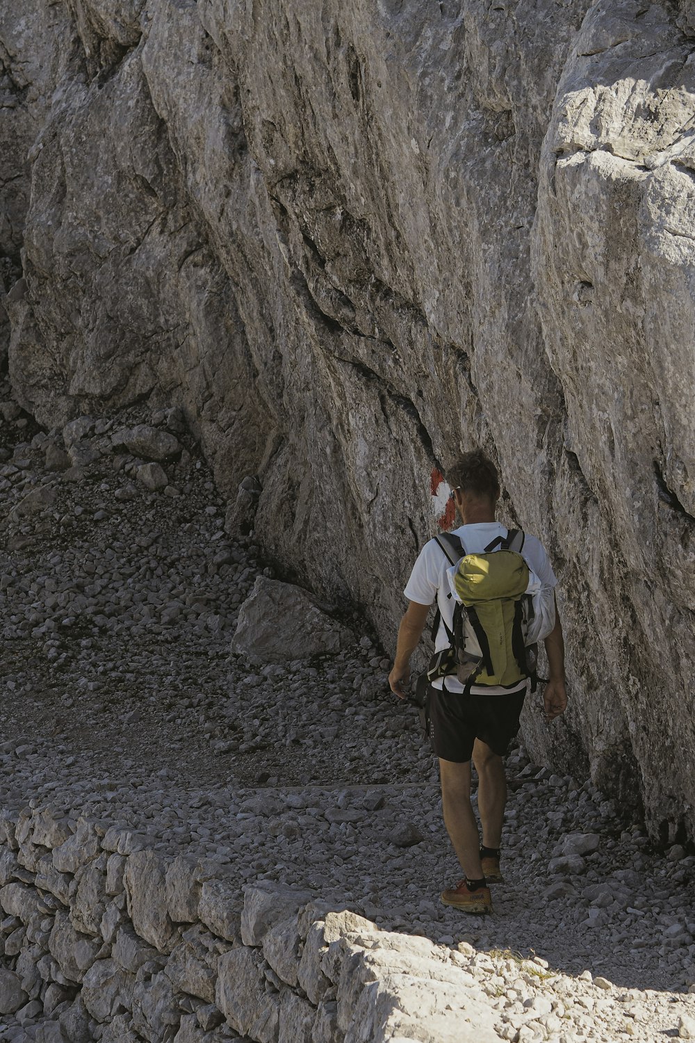 a man with a backpack walking up a rocky path
