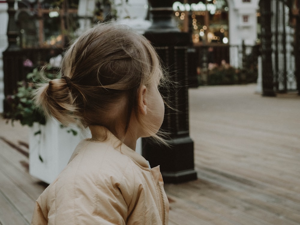 a little girl standing on a wooden deck