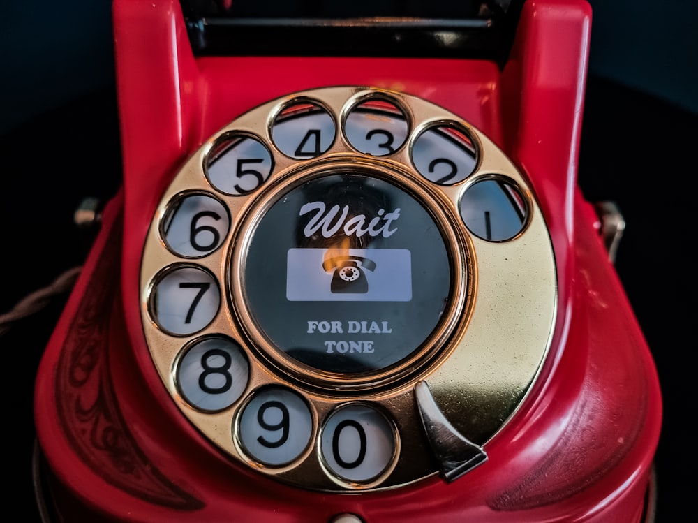 an old red rotary telephone with a dial on it
