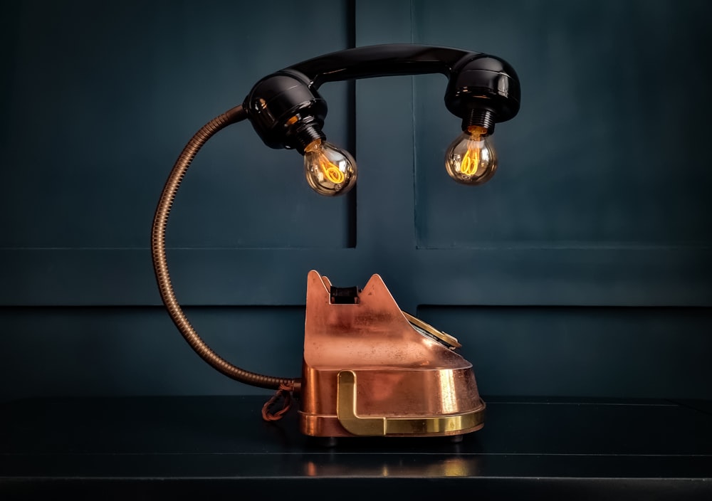um candeeiro de mesa com uma base de cobre e duas lâmpadas