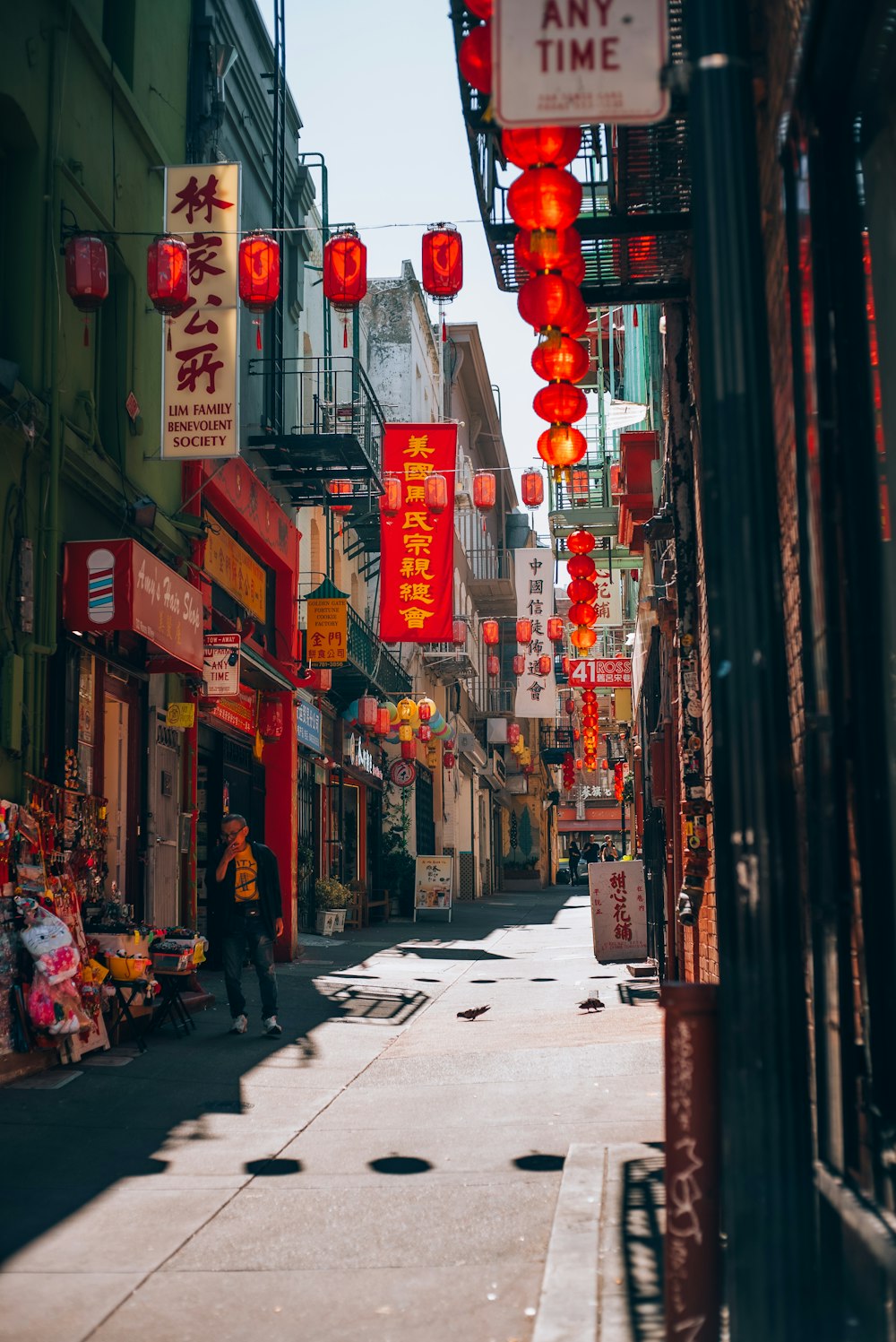 a narrow city street with red lanterns hanging from the buildings