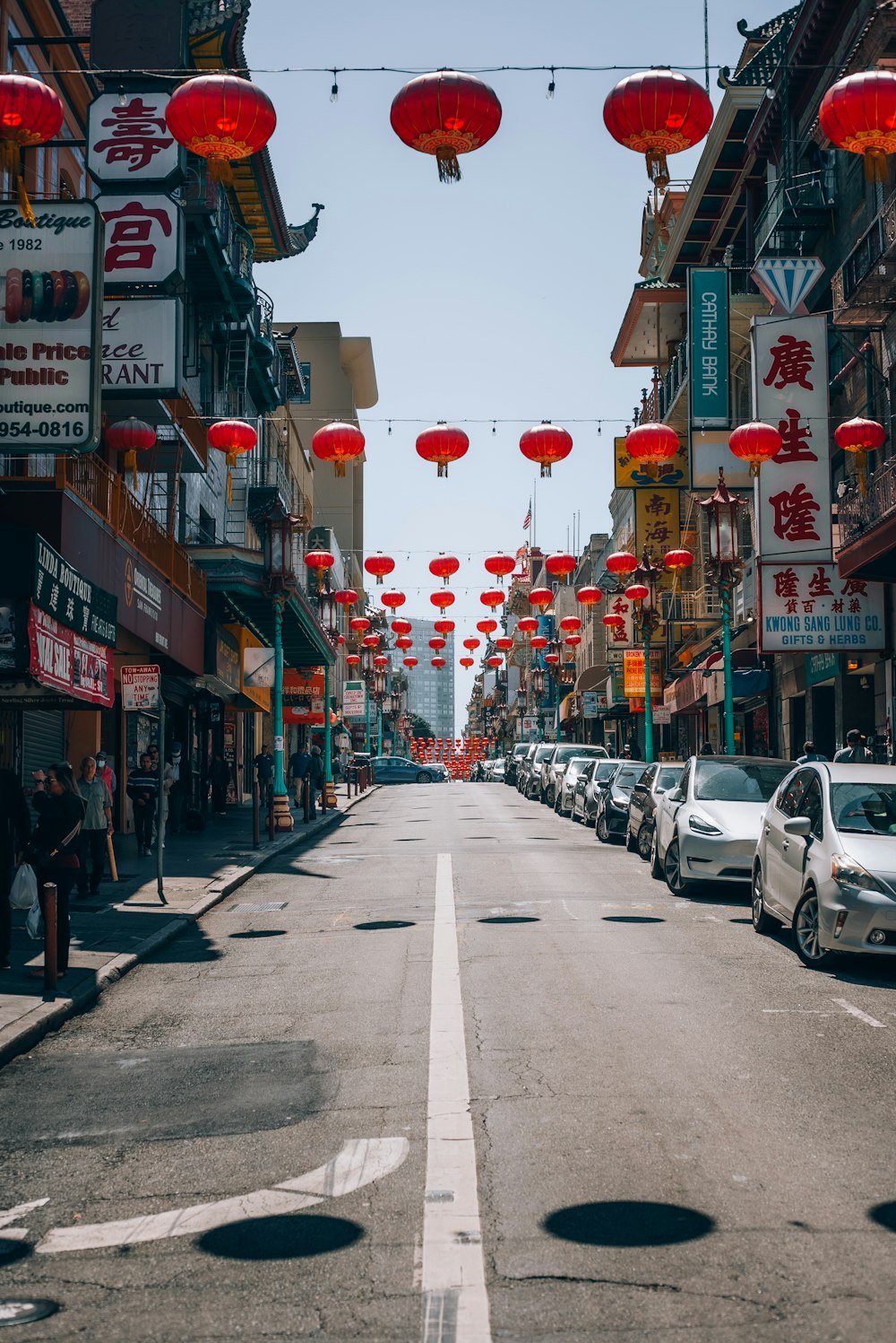 a street lined with red lanterns and parked cars