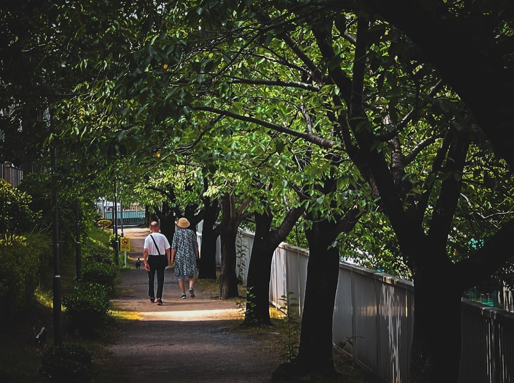 a couple of people walking down a dirt road