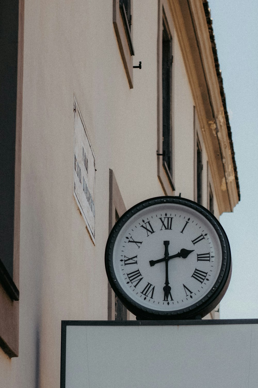a clock on top of a sign in front of a building
