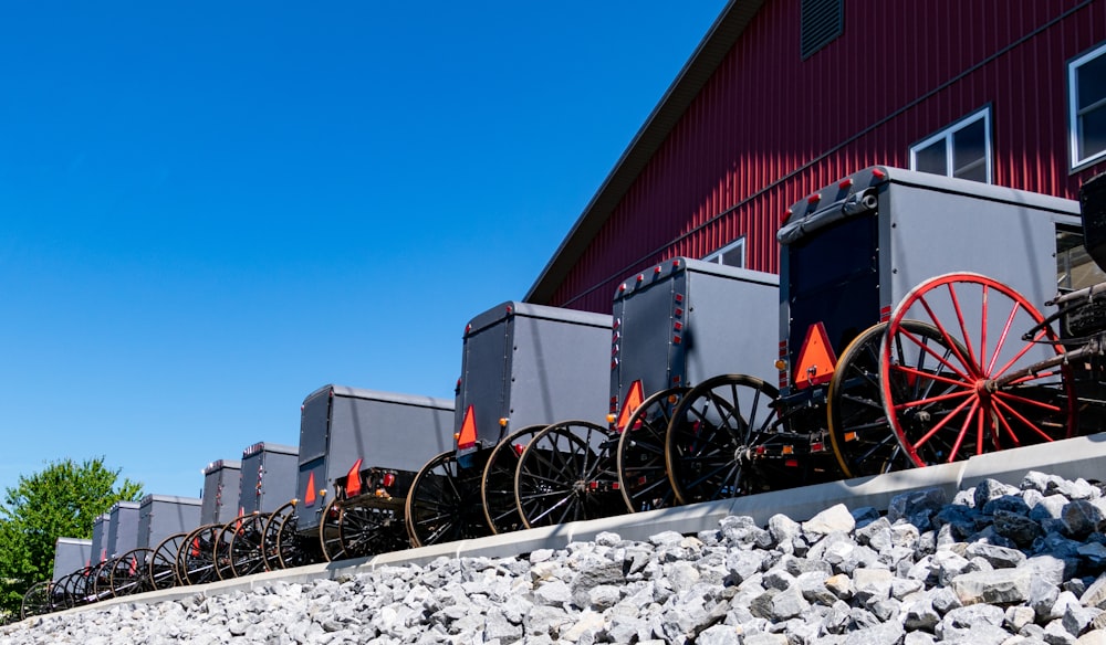 a row of old wagons sitting next to a red building