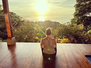 Sunrise yoga session on a wooden deck overlooking lush green hills.